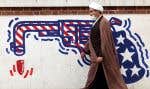Un mollah iranien marche devant une murale antiaméricaine à Téhéran, le 12 mars 2022.